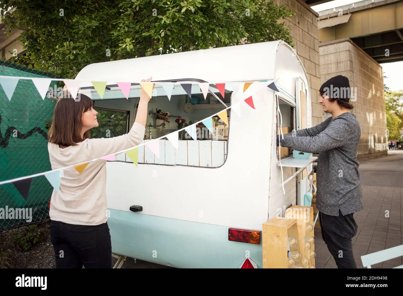 Uomini e donne che lavorano fuori camion cibo su strada Foto Stock