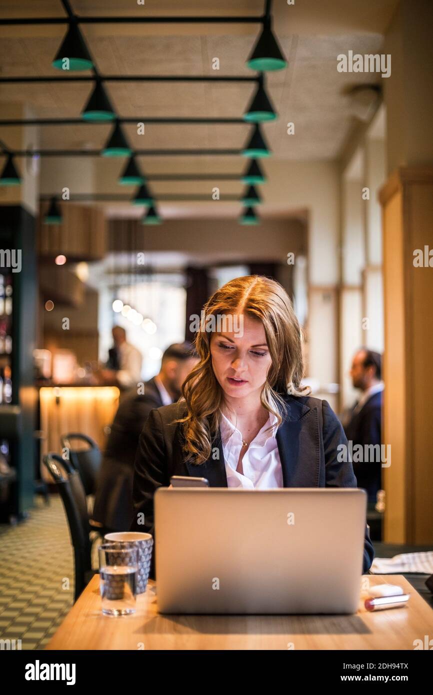 Donna d'affari che usa il telefono nel ristorante Foto Stock