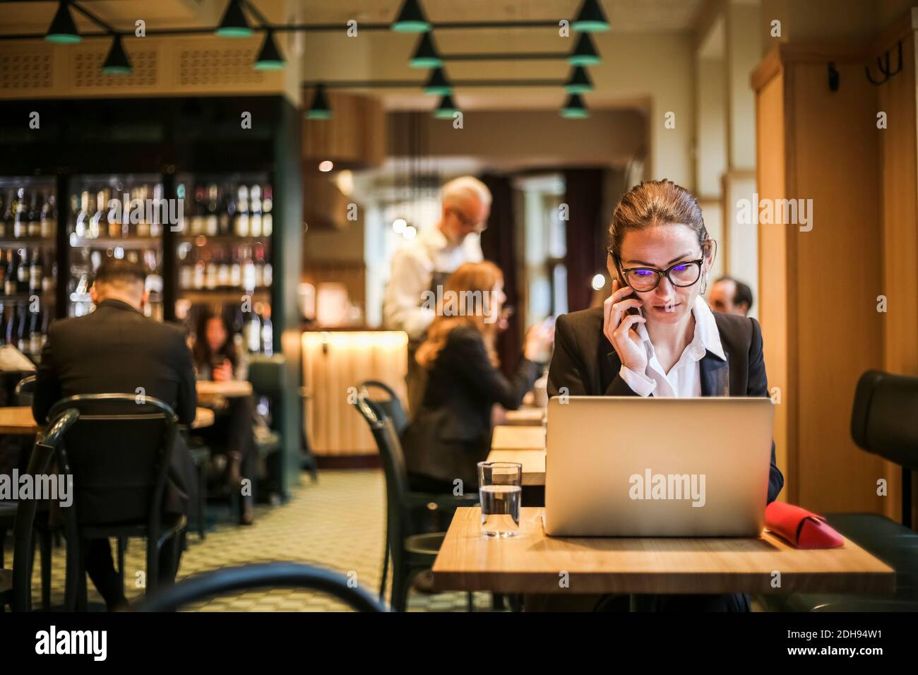Donna d'affari in bicchieri che parla al telefono nel ristorante Foto Stock