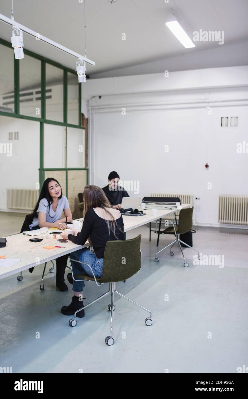 Due donne che discutono alla scrivania in ufficio creativo Foto Stock