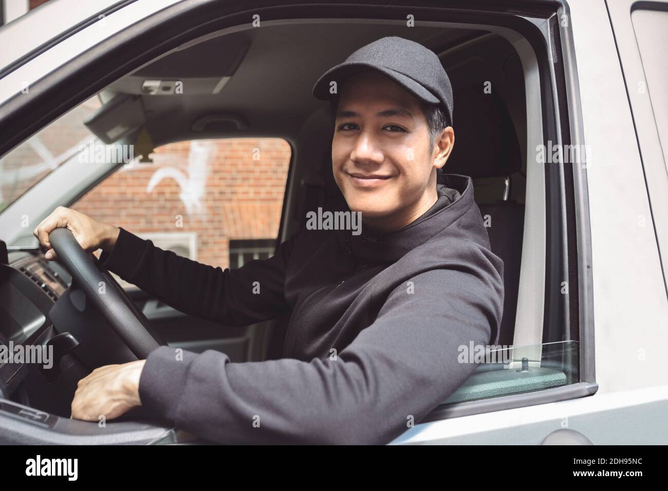 Ritratto di sorridente addetto alla consegna seduto sul camion Foto Stock