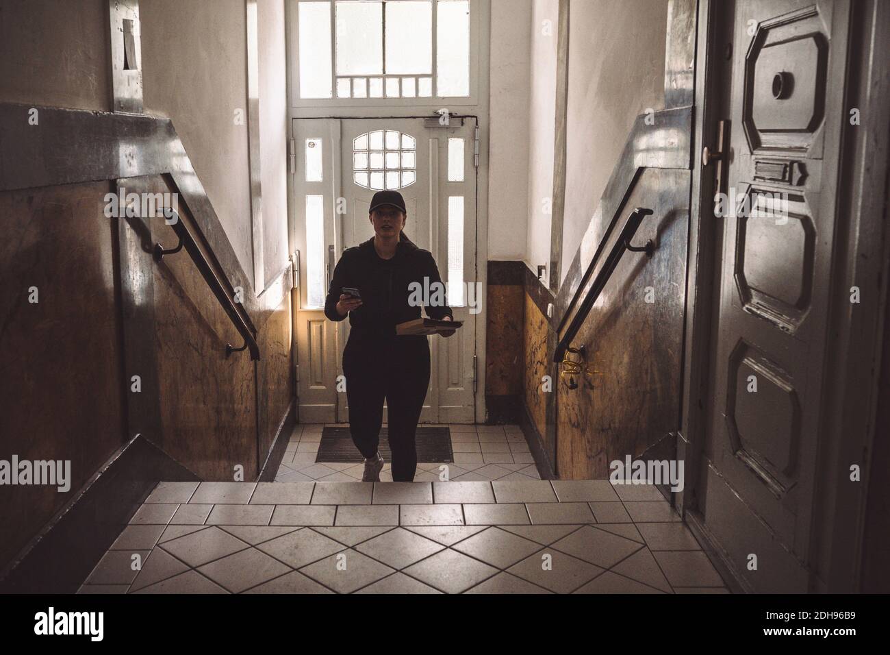 Ritratto di donna con telefono e scale di arrampicata pacchetto contro la porta Foto Stock