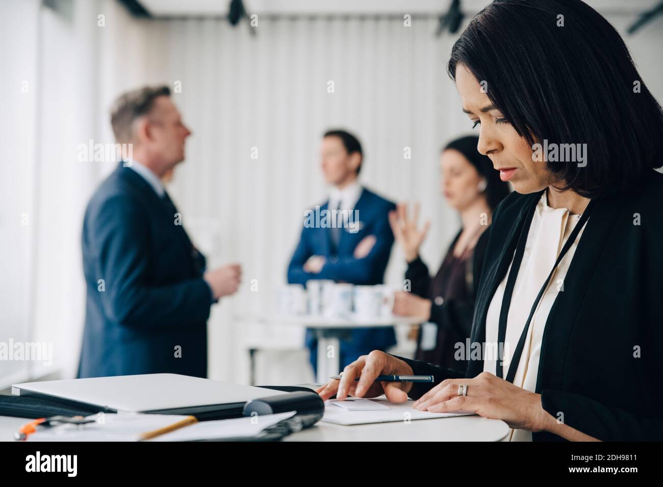 Persona di affari femminile in piedi al tavolo nel posto di lavoro dell'ufficio Foto Stock