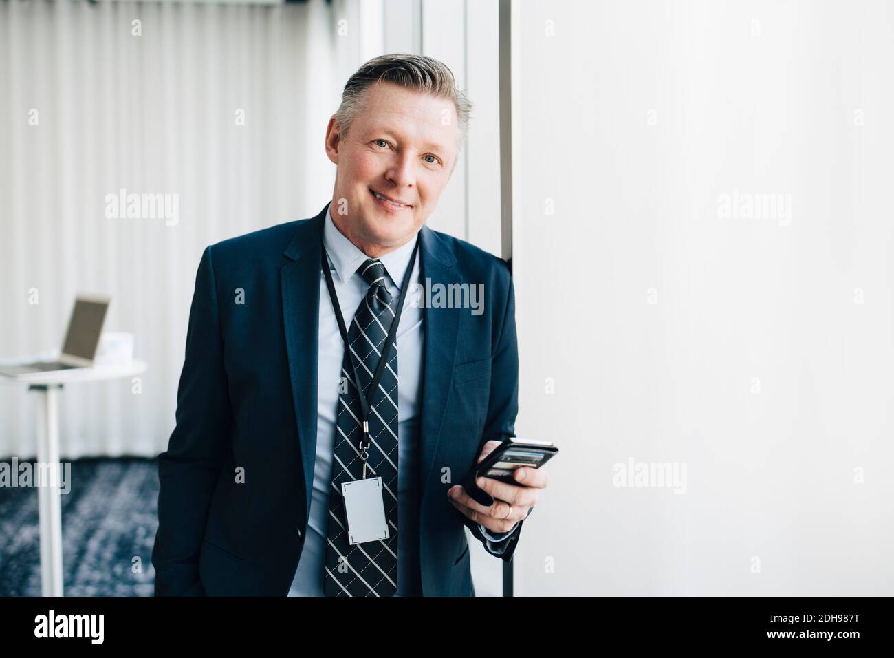 Ritratto di imprenditore sorridente con telefono cellulare in ufficio Foto Stock