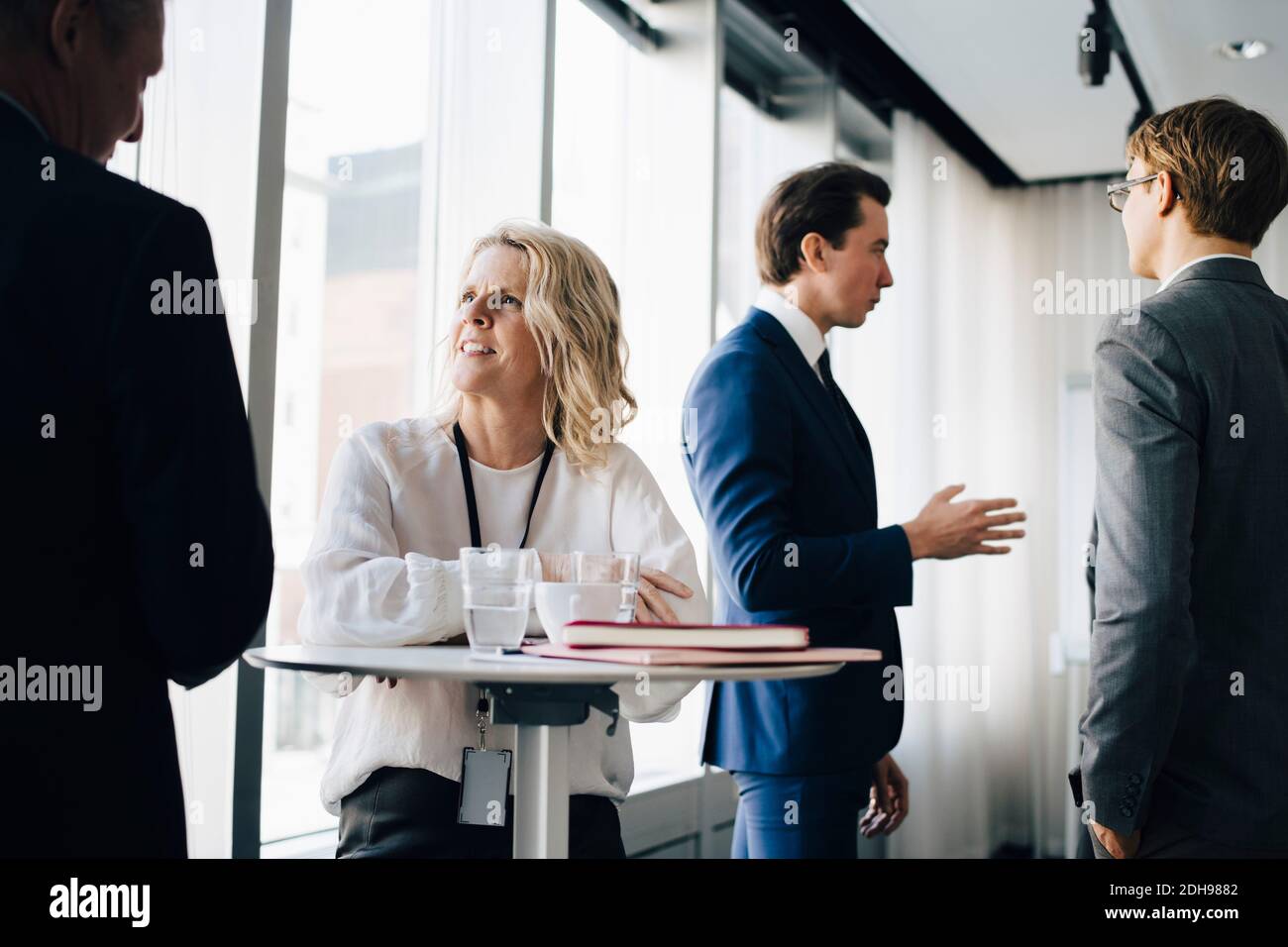 Donna imprenditore che parla con la collega mentre la collega è in piedi in background sul posto di lavoro Foto Stock