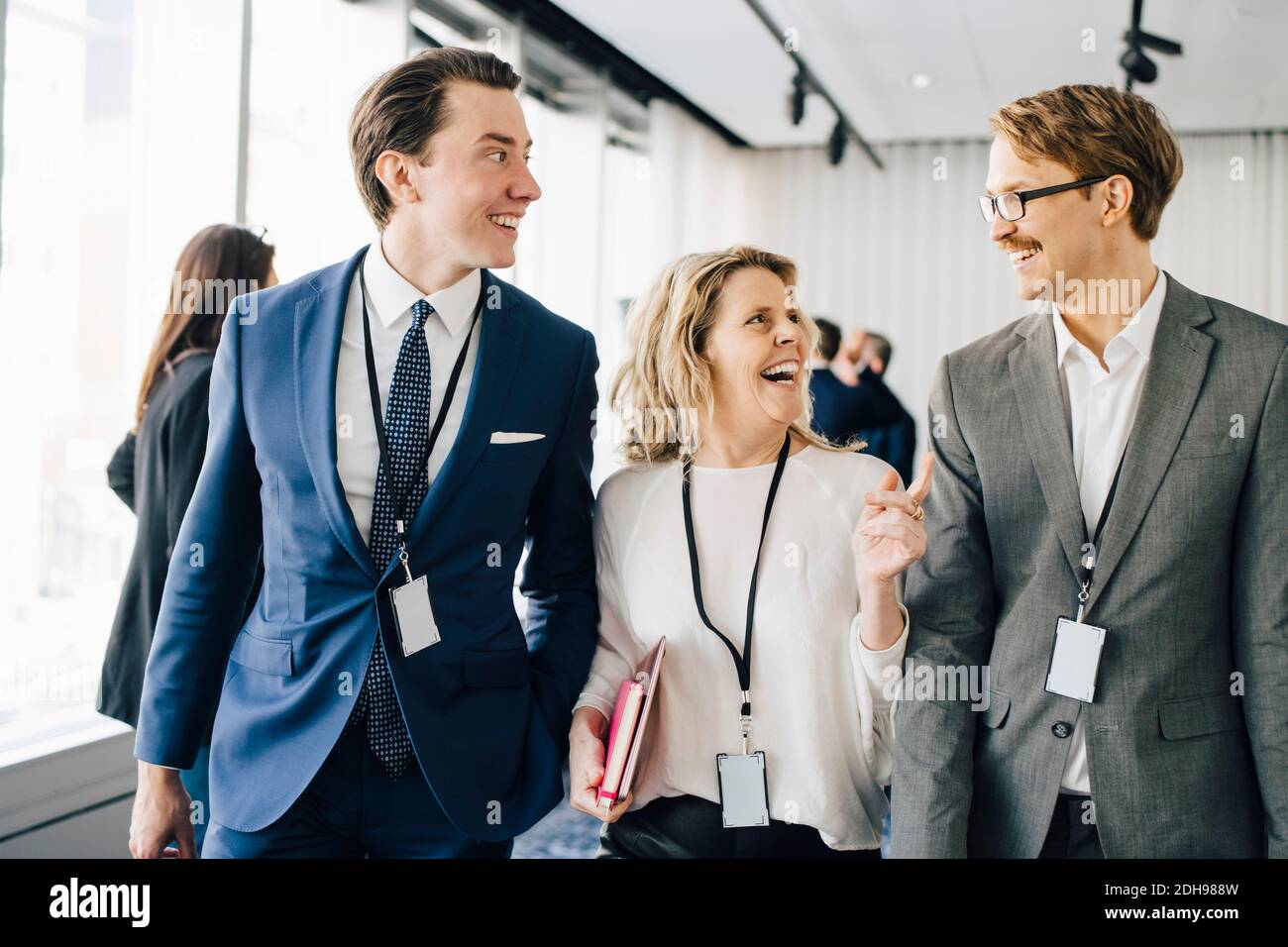 Felice donna che cammina con i colleghi in ufficio Foto Stock