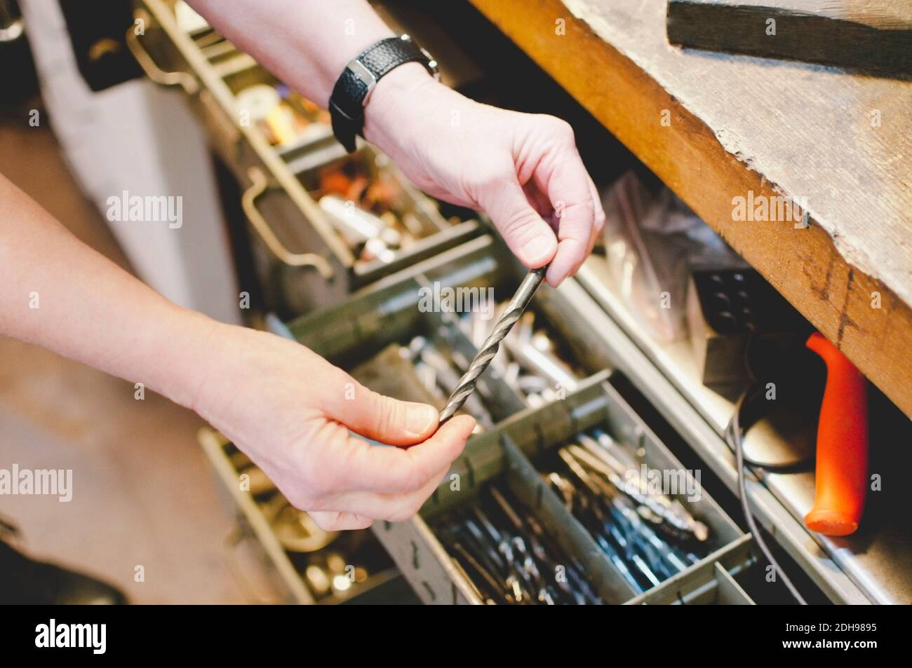 Immagine ritagliata di un'anziana persona che tiene la punta di perforazione in gioielli officina Foto Stock