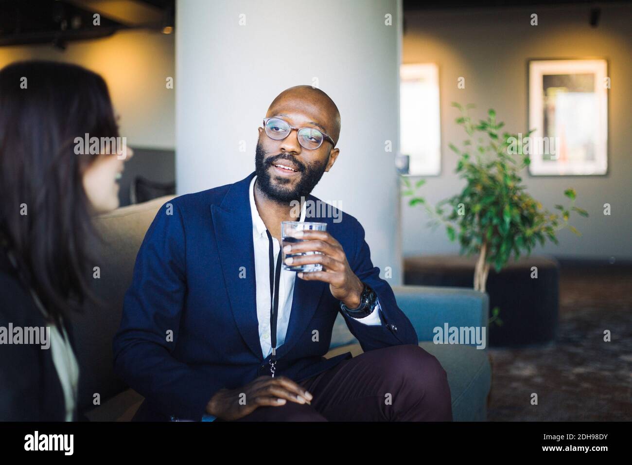 Uomo d'affari con bicchiere che guarda il collaboratore in ufficio Foto Stock