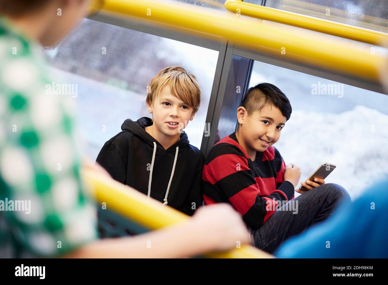 Ragazzi che guardano via mentre si appoggiano sul vetro nella scuola media Foto Stock