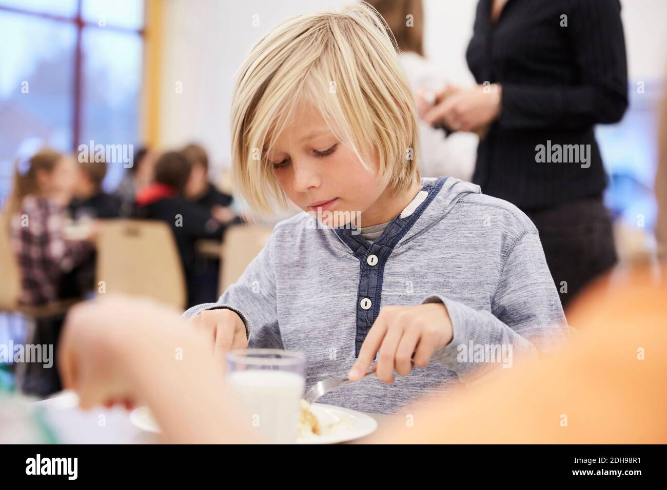 Ragazzo che pranza nella caffetteria della scuola Foto Stock