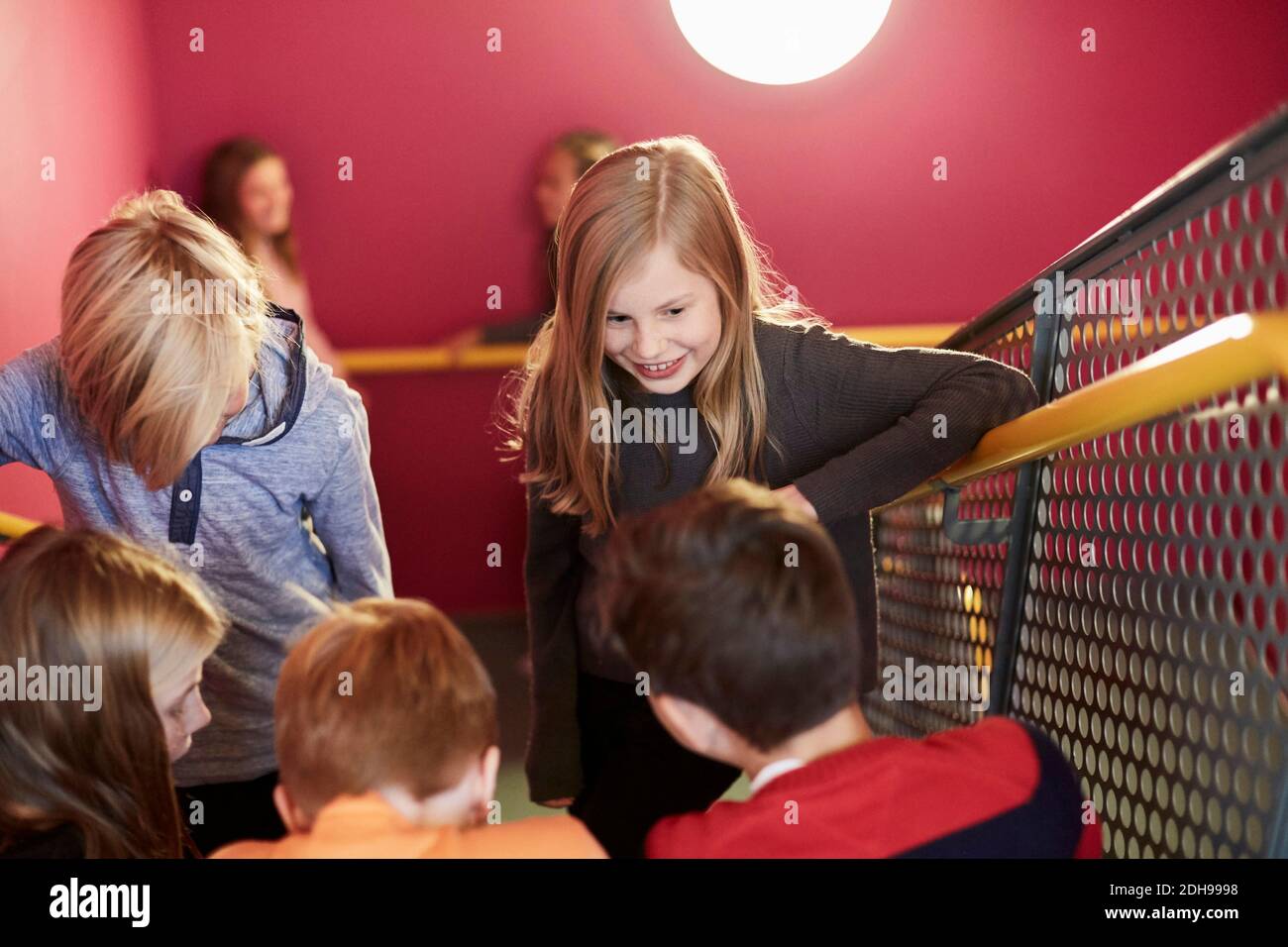 Sorridente ragazza con gli amici sulla scala della scuola media Foto Stock