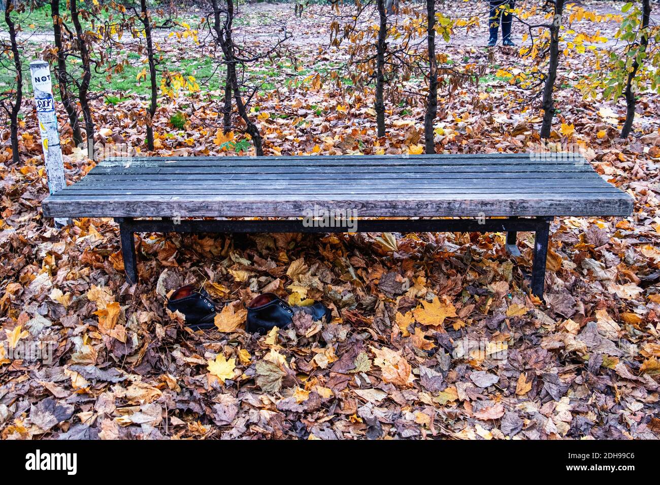 Abbandonate, in dumping, disusate, indesiderate scarpe da ginnastica nere accanto alla panchina di legno a Rosenthaler Strasse, Mitte, Berlino Foto Stock