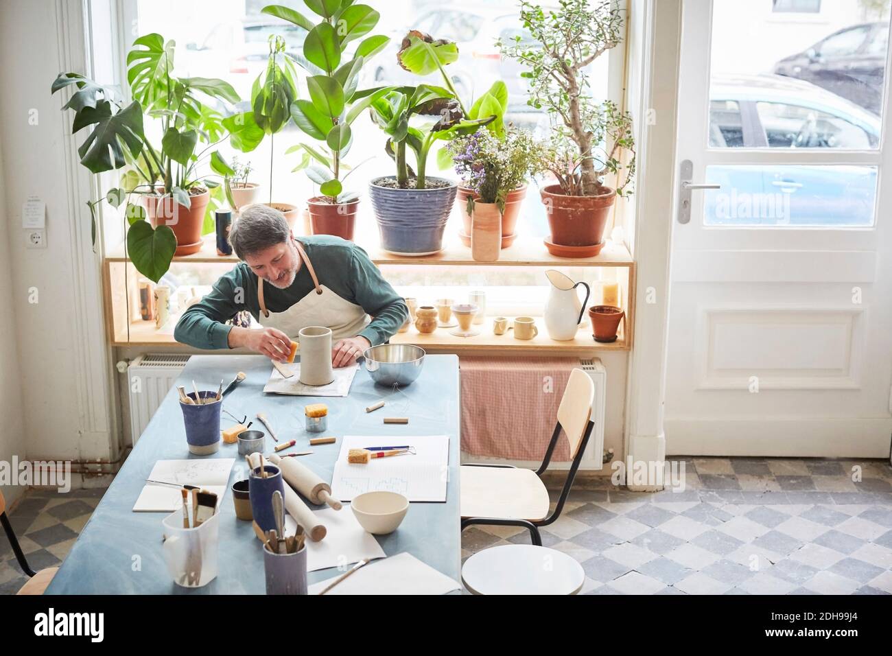 Uomo maturo che fa il prodotto artigianale a tavola in classe ceramica Foto Stock