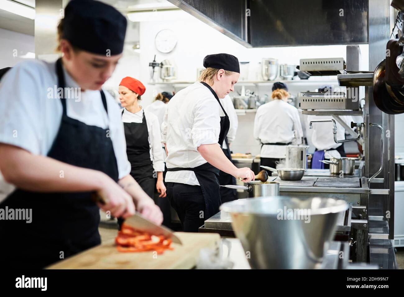 Insegnante maturo con gli studenti dello chef che cucinano in cucina commerciale Foto Stock