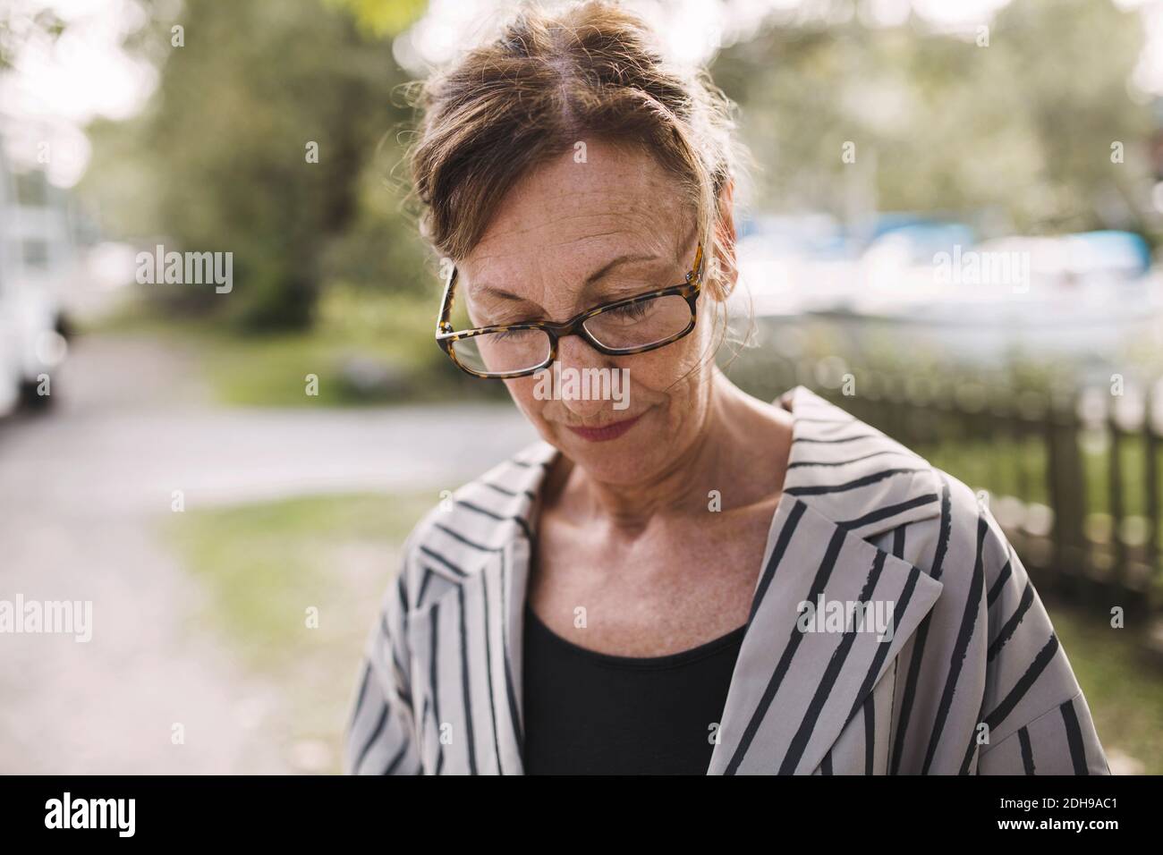 Uomo d'affari che guarda in basso mentre si trova al parco Foto Stock