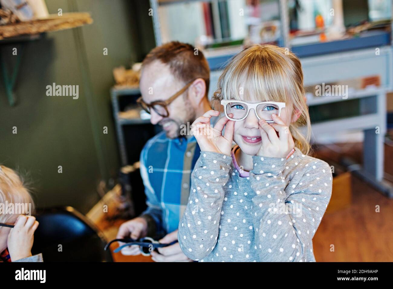 Ritratto di ragazza che indossa occhiali con la famiglia in officina Foto Stock