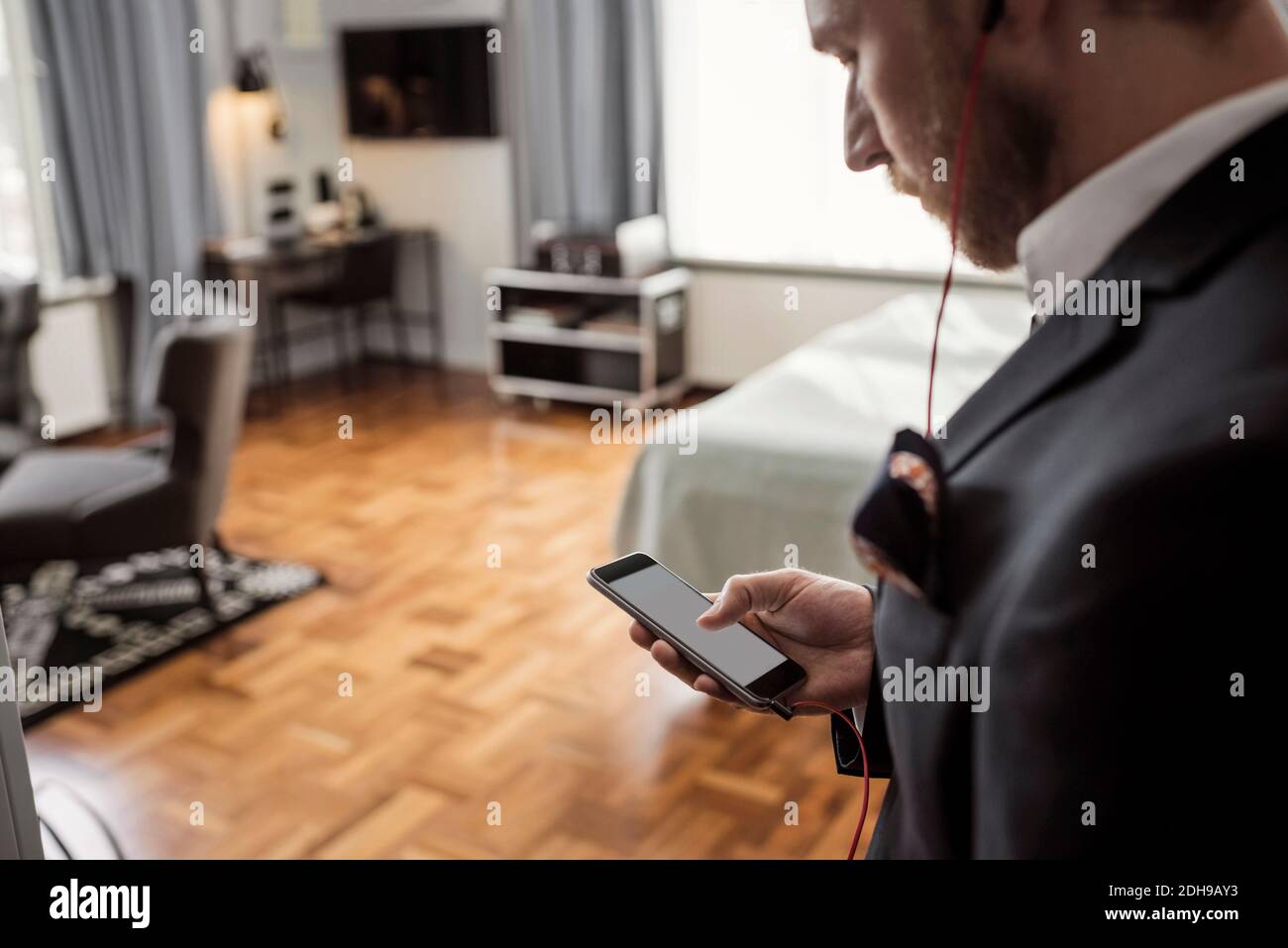 Visualizzazione ad alto angolo della messaggistica di testo di un uomo d'affari tramite telefono cellulare in camera d'albergo Foto Stock