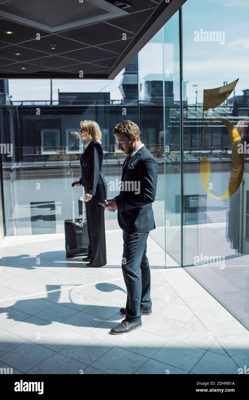 Vista laterale degli uomini d'affari che si trovano nel corridoio dell'hotel Foto Stock