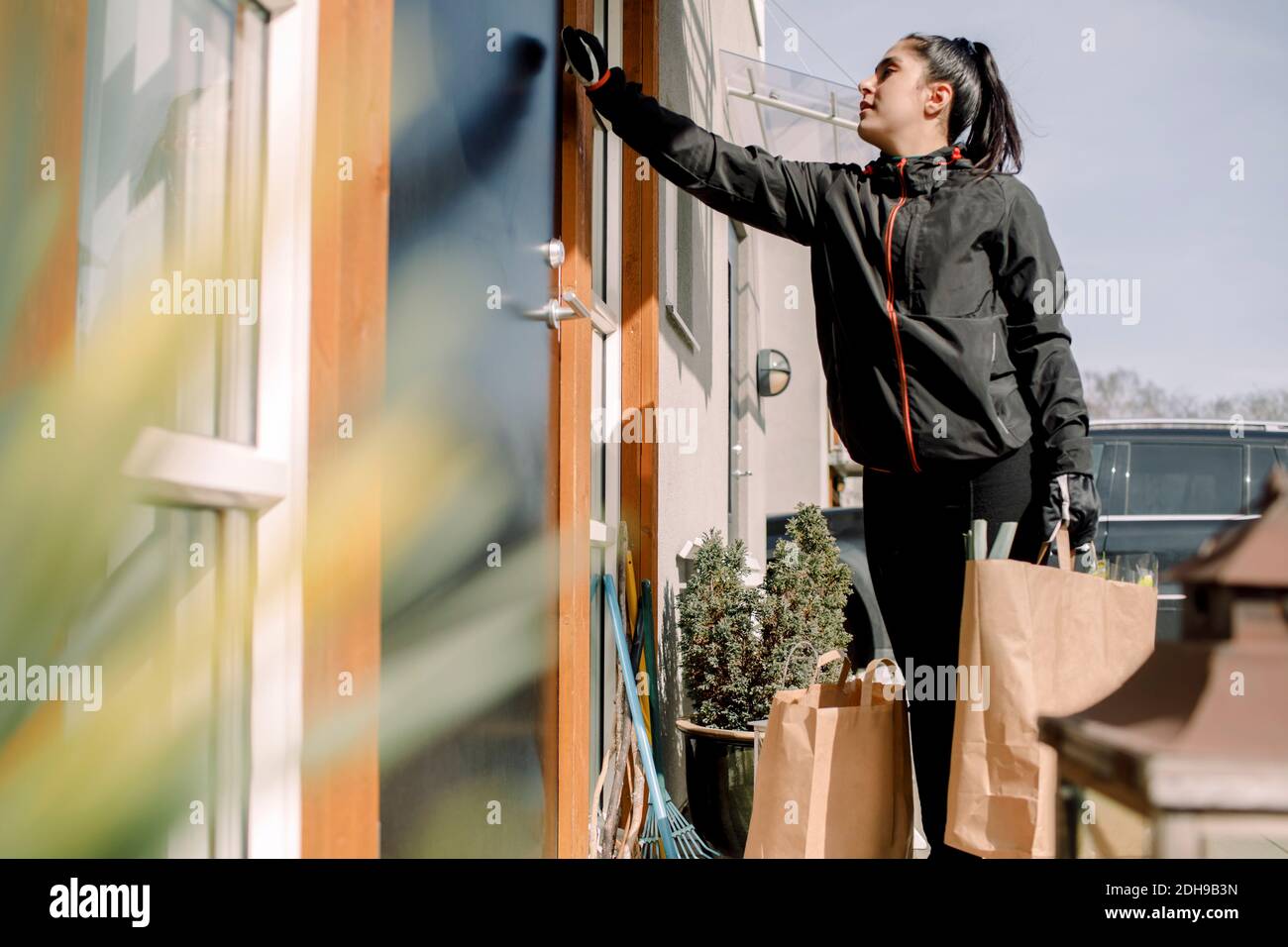 Consegna donna che consegna generi alimentari all'ingresso della casa Foto Stock