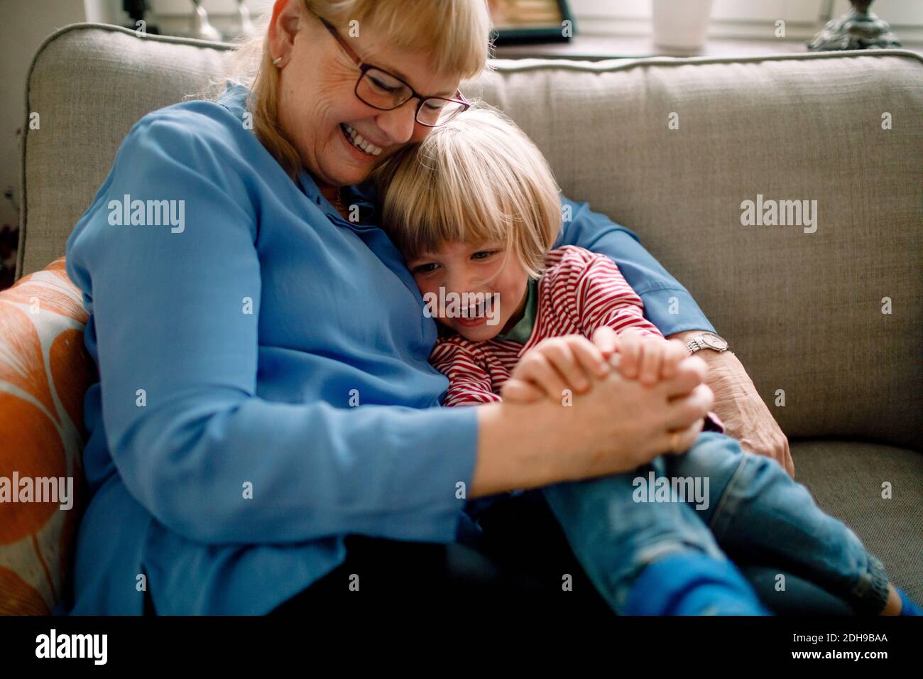 Ragazzo felice seduto con nonna sul divano a casa Foto Stock