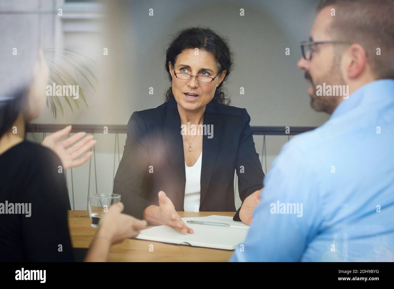 Sicuro avvocato donna matura discutere con l'uomo d'affari e la donna d'affari durante incontro in ufficio Foto Stock