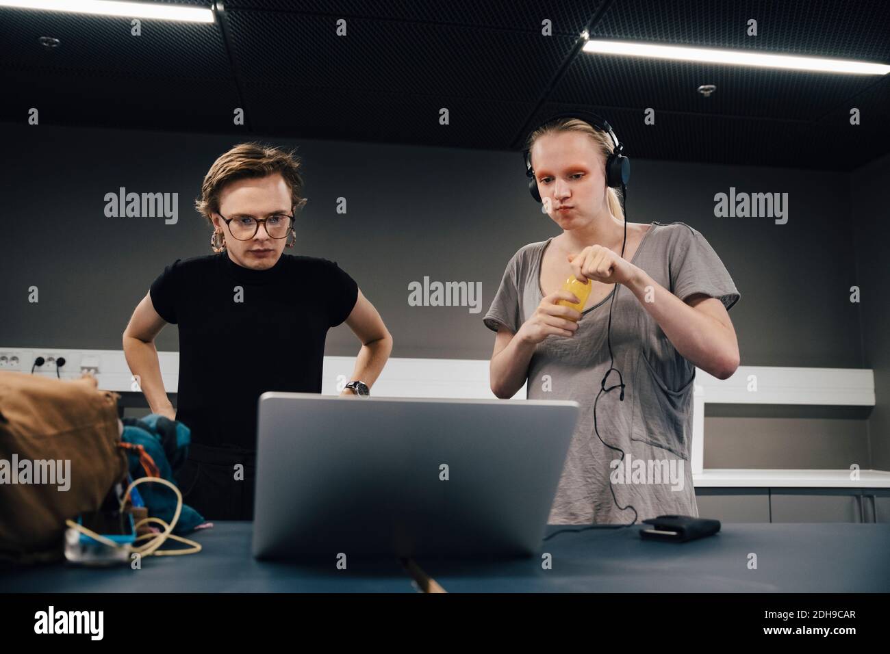 Giovani colleghi che guardano il computer portatile mentre si trovano in ufficio Foto Stock