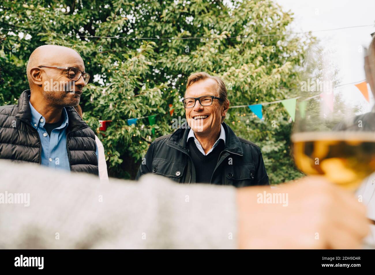 Sorridenti anziani che godono di festa in giardino in cortile Foto Stock