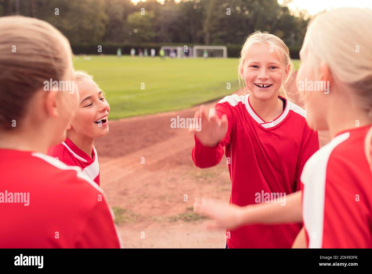 Felice atlete in piedi contro il campo di calcio Foto Stock