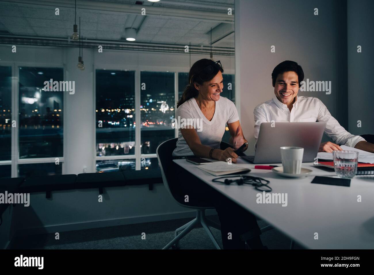 Sorridente uomo d'affari e una strategia di pianificazione uomo d'affari mentre si guarda il laptop in ufficio Foto Stock