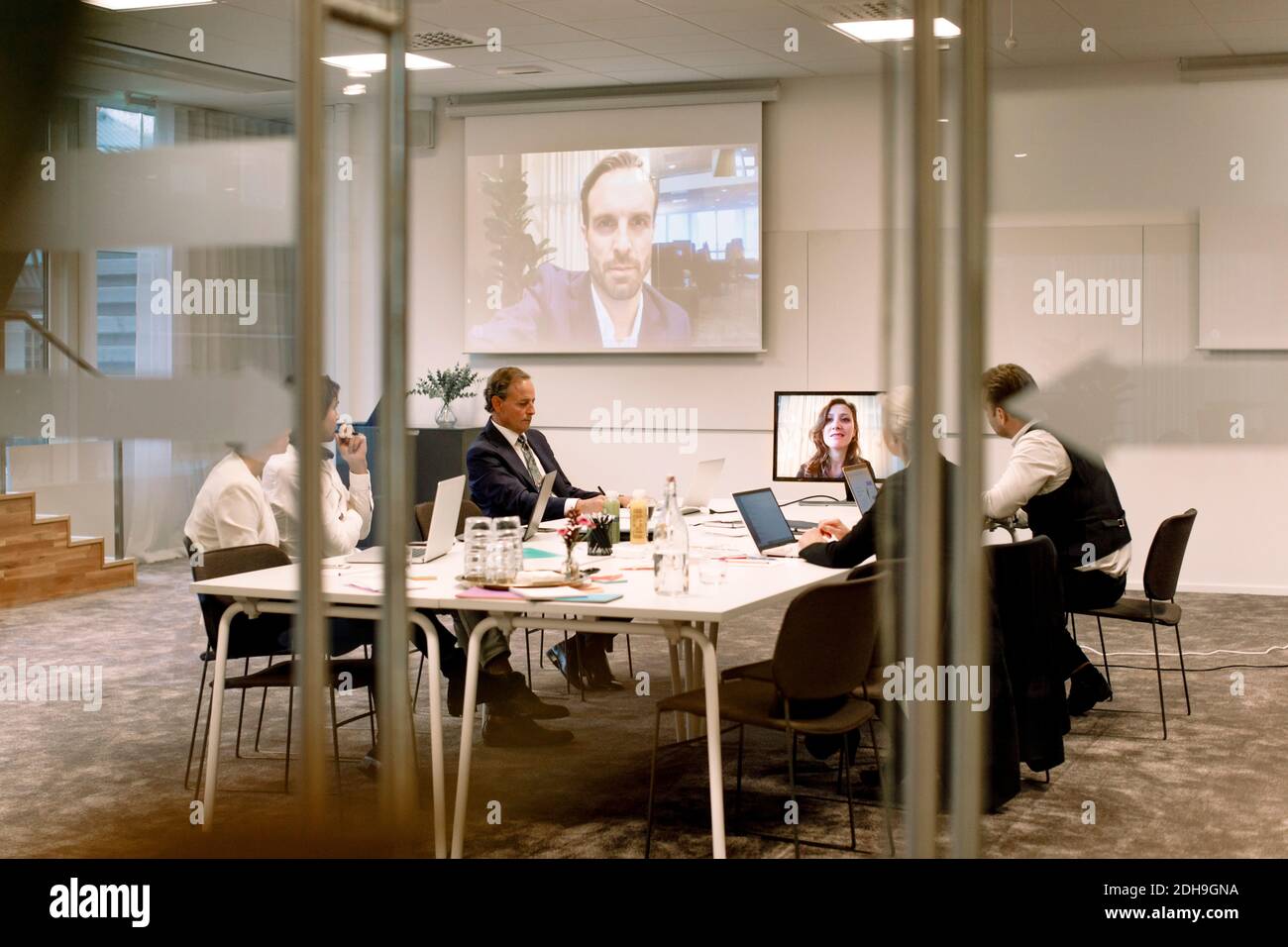 I dirigenti aziendali discutono durante una riunione durante una conferenza Web vetro in ufficio Foto Stock