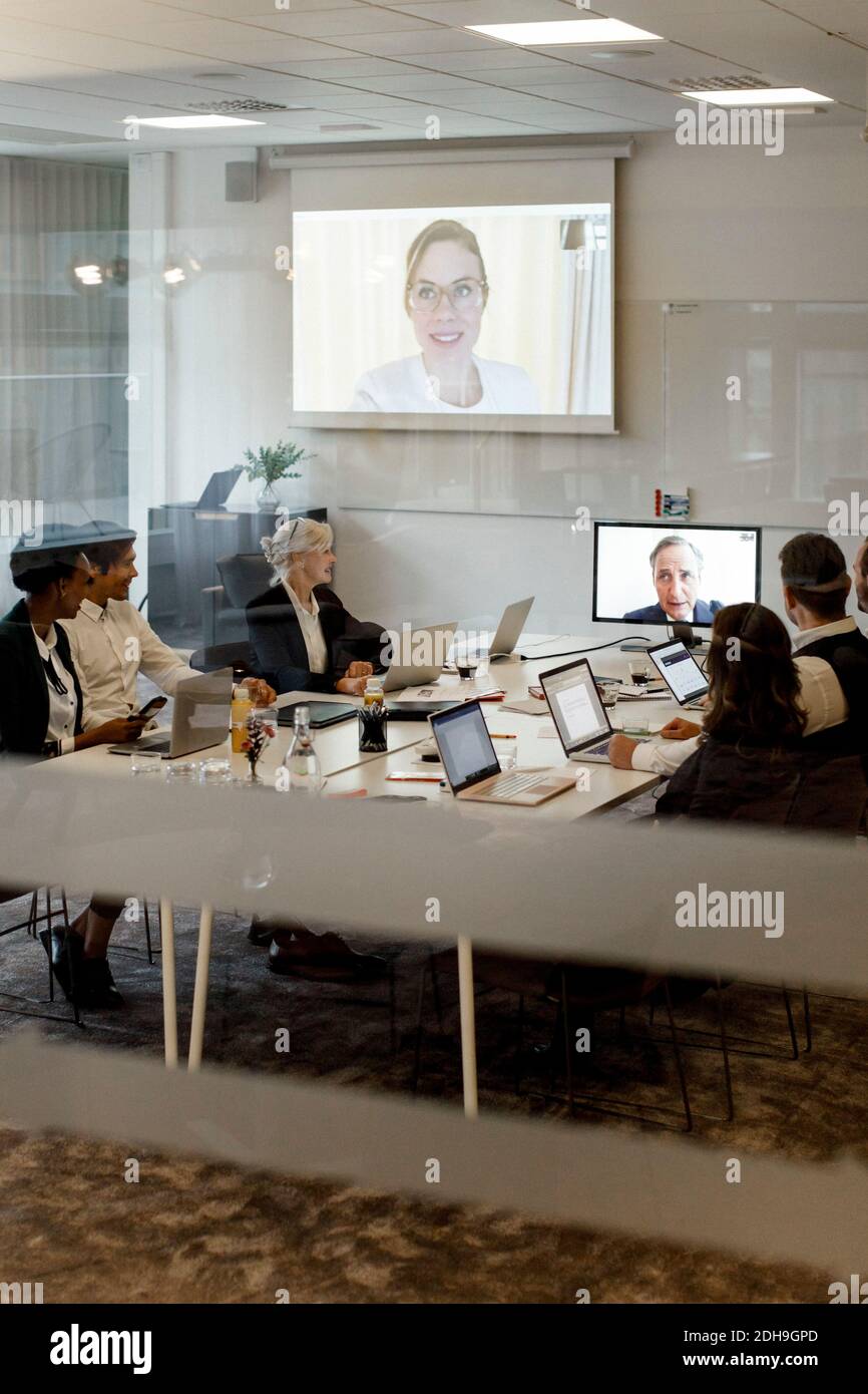 Gli uomini d'affari discutono durante la conferenza globale nella riunione della sala riunioni in ufficio Foto Stock