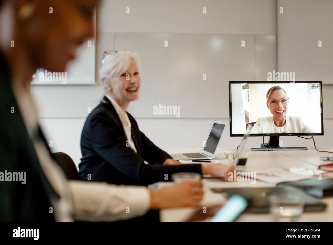 Sorridente manager femminile che discute con i colleghi attraverso la conferenza web durante riunione aziendale globale Foto Stock
