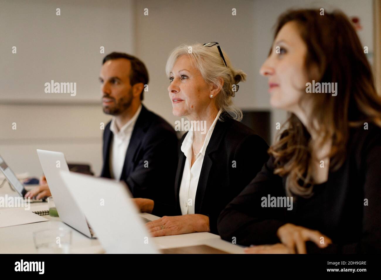 Dirigenti di sesso maschile e femminile che utilizzano computer portatili al tavolo per conferenze riunione di ufficio Foto Stock