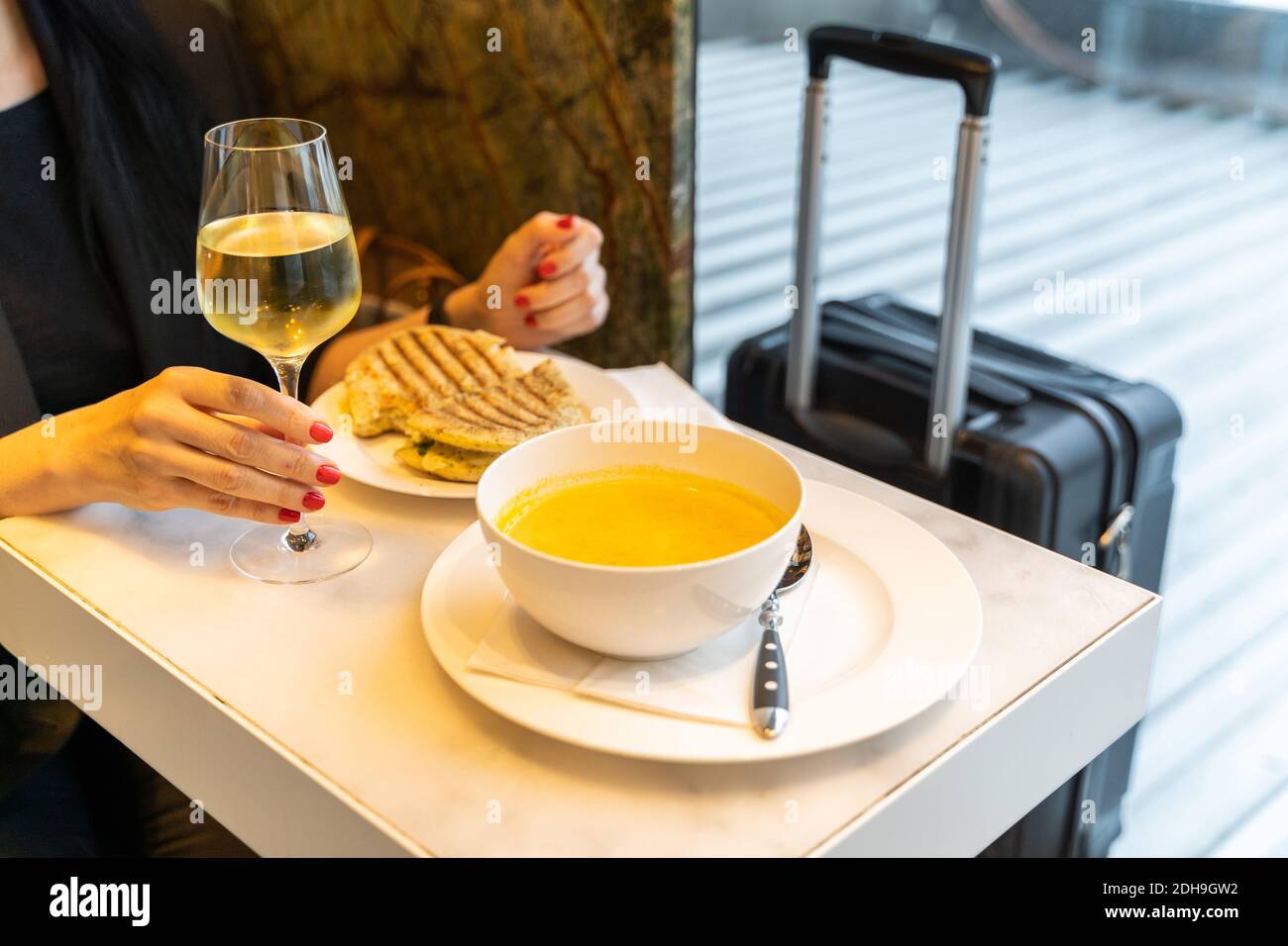 Donna che ha una bevanda con zuppa e sandwich in un ristorante aeroporto Foto Stock
