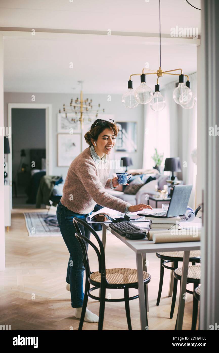 Donna che accede a una riunione online lavorando a casa Foto Stock