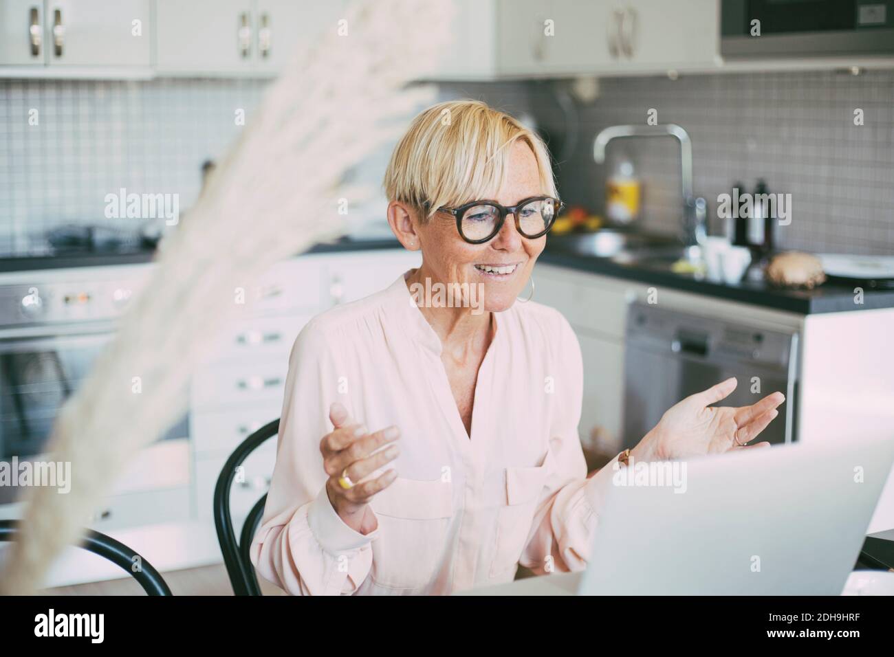 Donna in cucina che ha una riunione in linea che lavora a casa Foto Stock