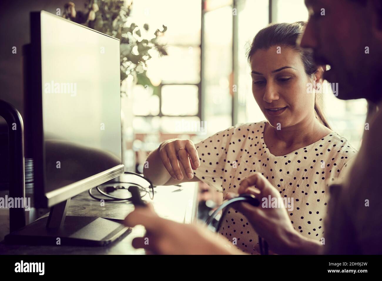 Cavi di regolazione del monitor del computer per utenti di sesso maschile e femminile in caffè Foto Stock