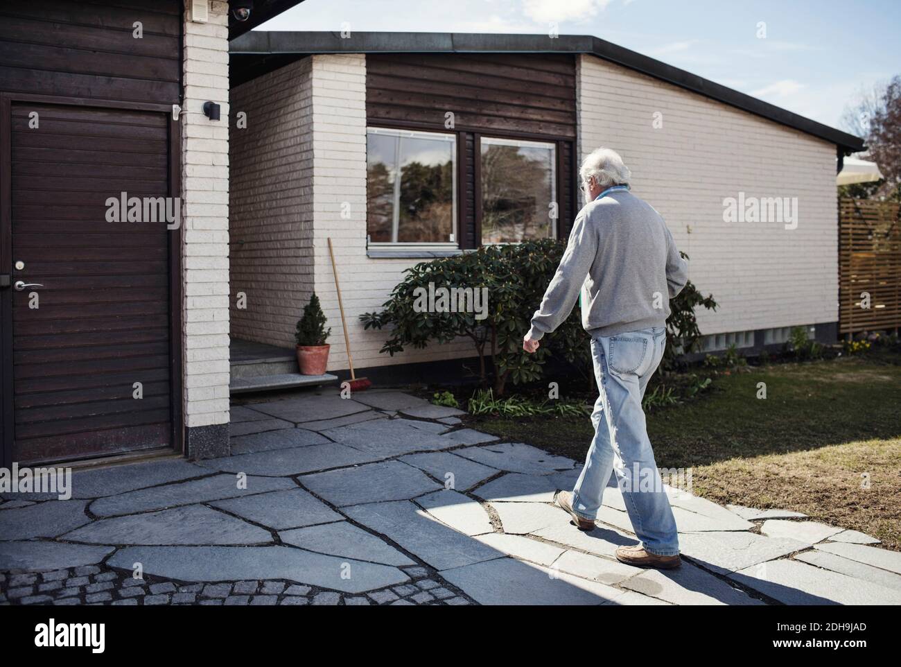 Lunghezza completa dell'uomo anziano che cammina verso casa al sole giorno Foto Stock