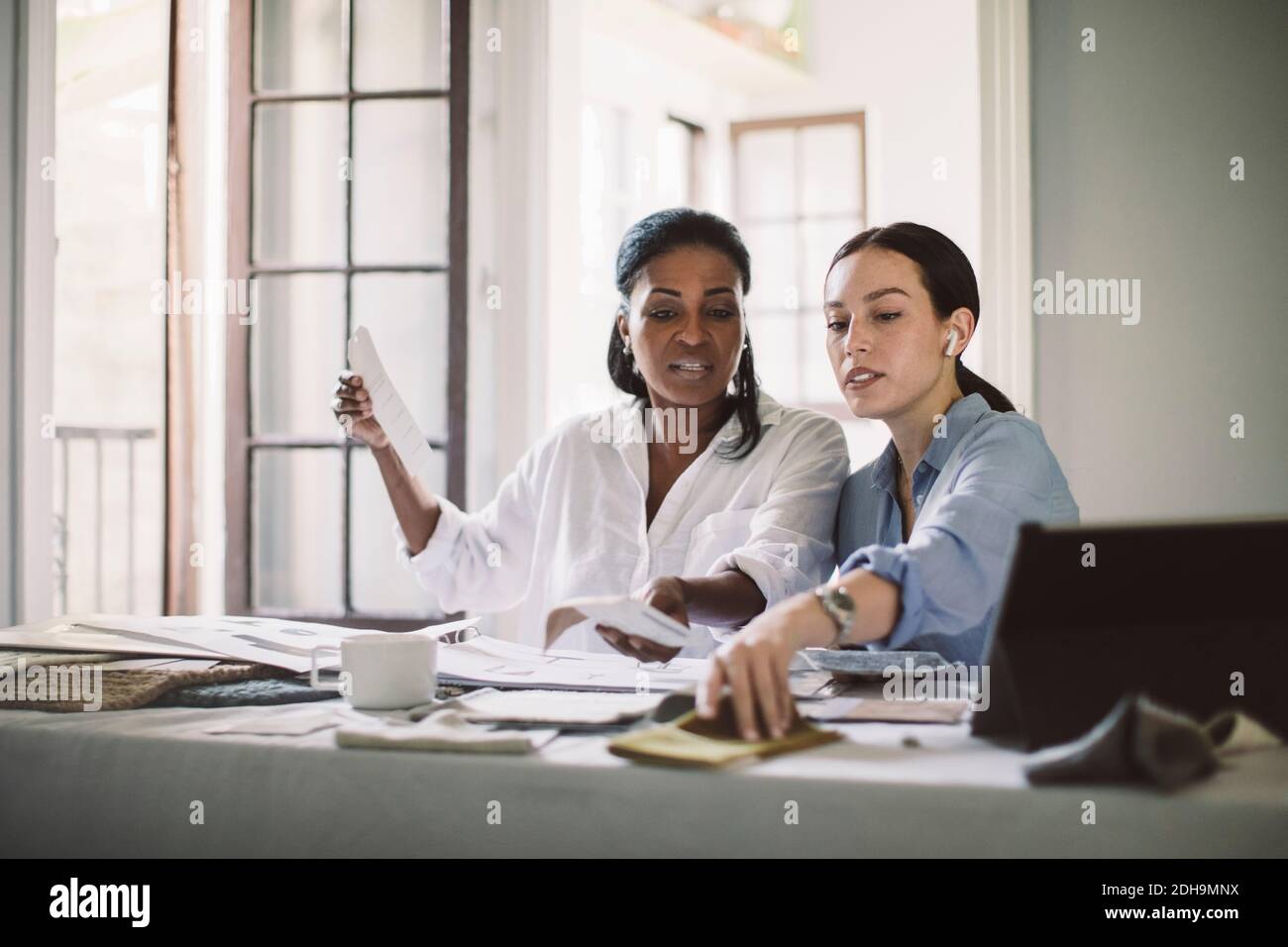 Le donne architetti discutono mentre lavorano al tavolo in ufficio domestico Foto Stock