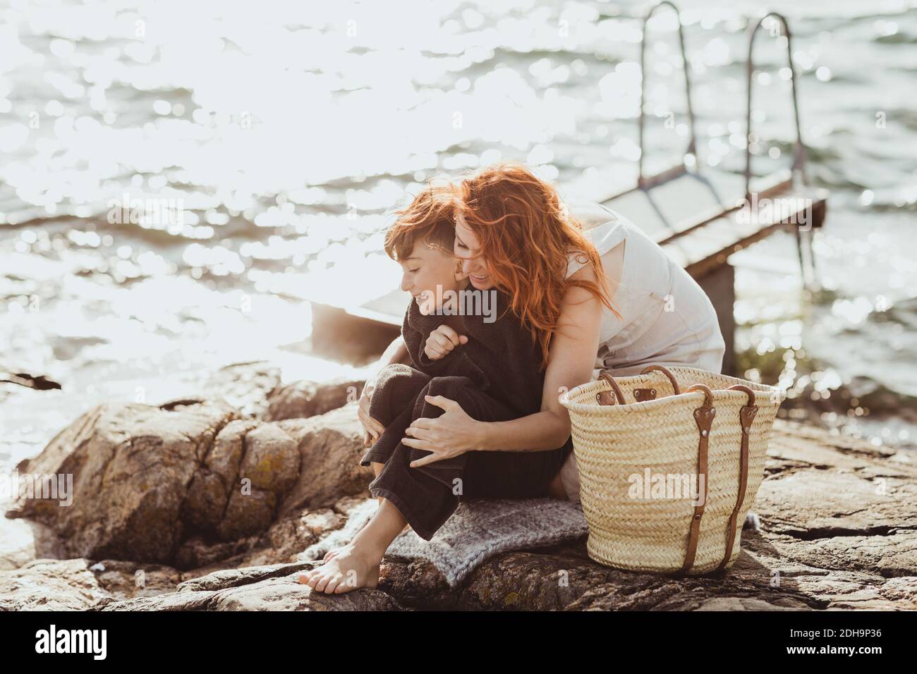 Madre abbracciando il figlio da dietro contro il mare durante la giornata di sole Foto Stock