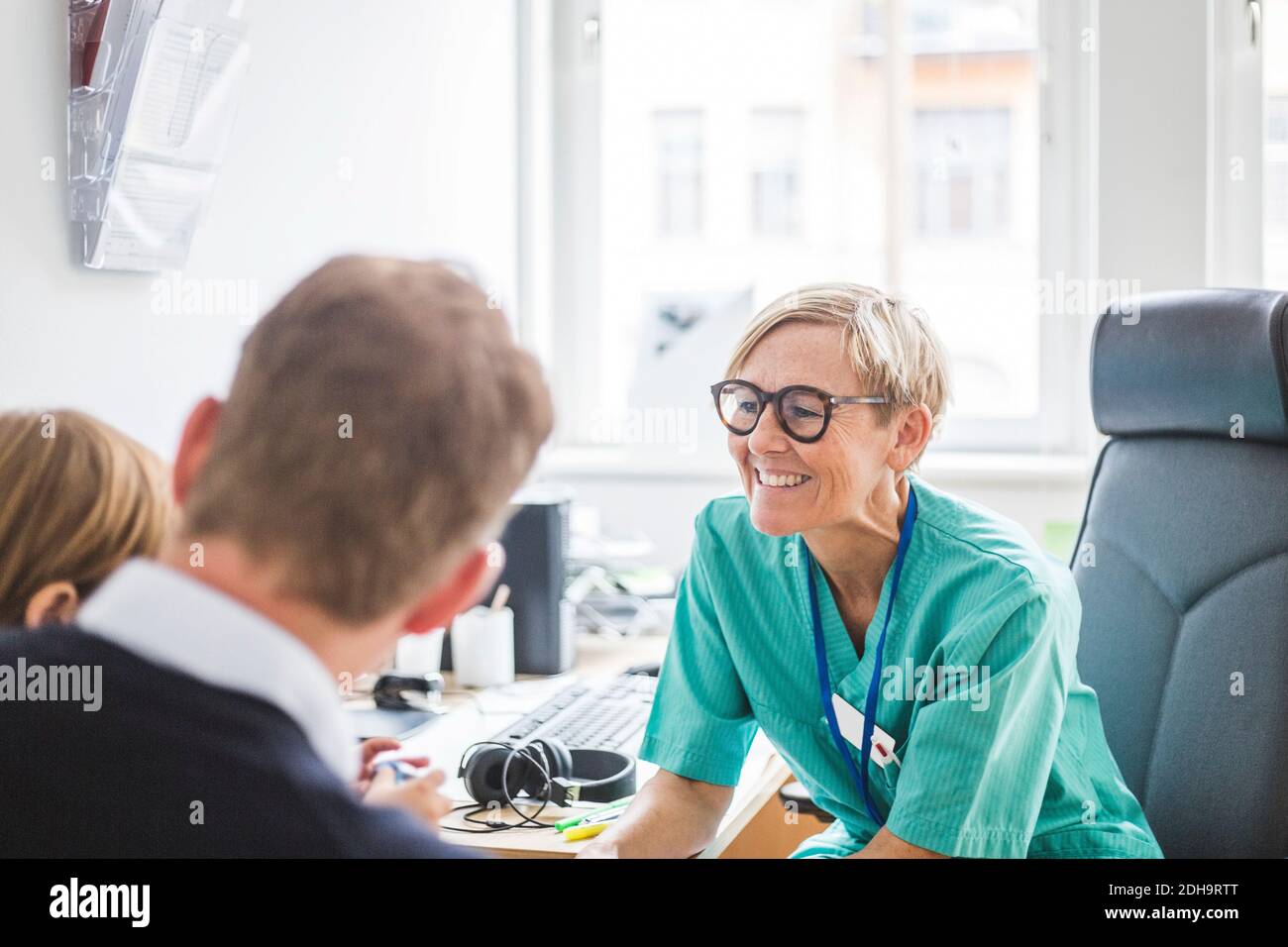 Sorridente medico maturo che parla con il padre in clinica Foto Stock