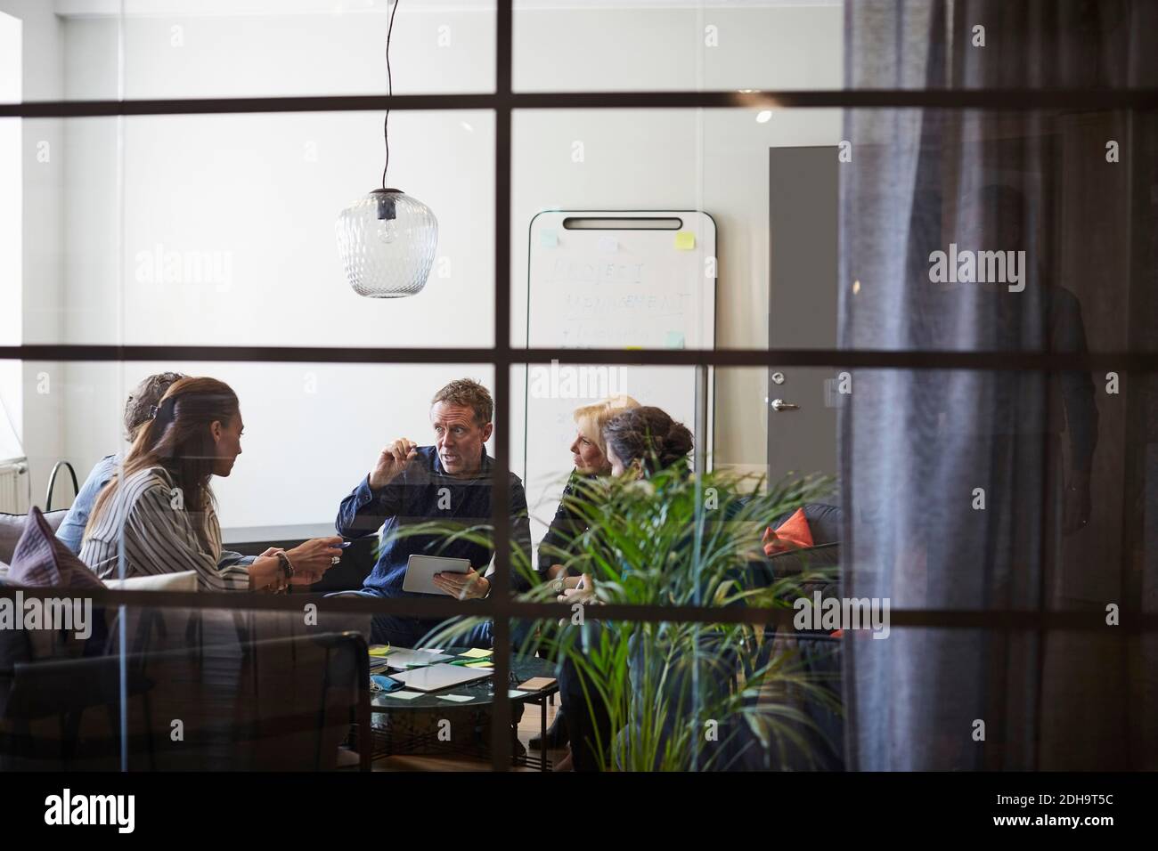 Il team aziendale è seduto nella sala riunioni durante la riunione vetro in ufficio Foto Stock