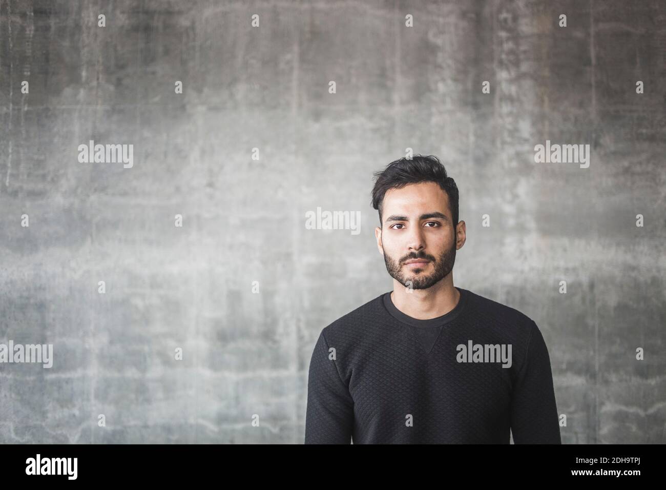 Ritratto di un giovane contemplante in piedi contro una parete grigia Foto Stock