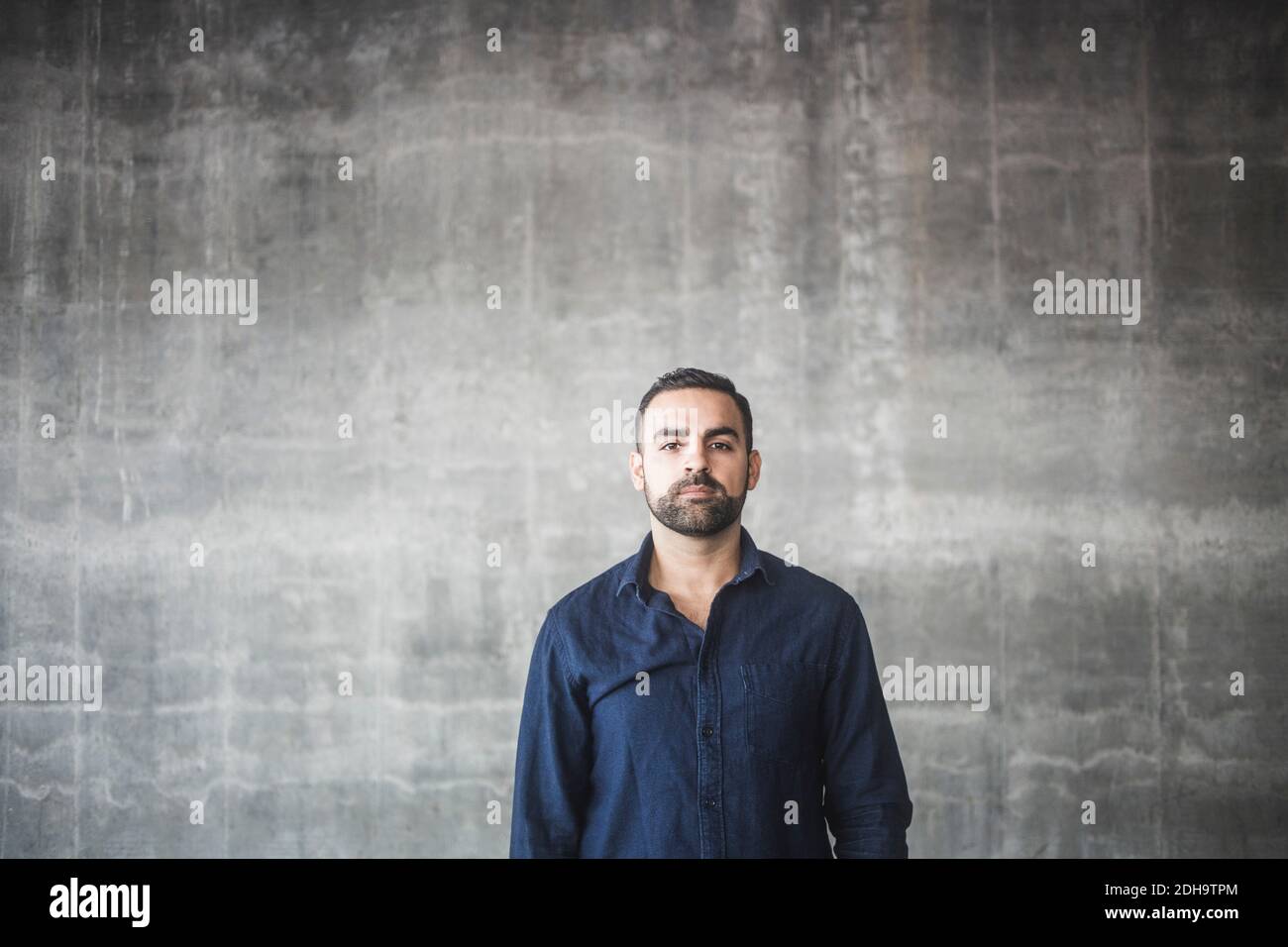 Ritratto dell'uomo in piedi contro la parete grigia Foto Stock