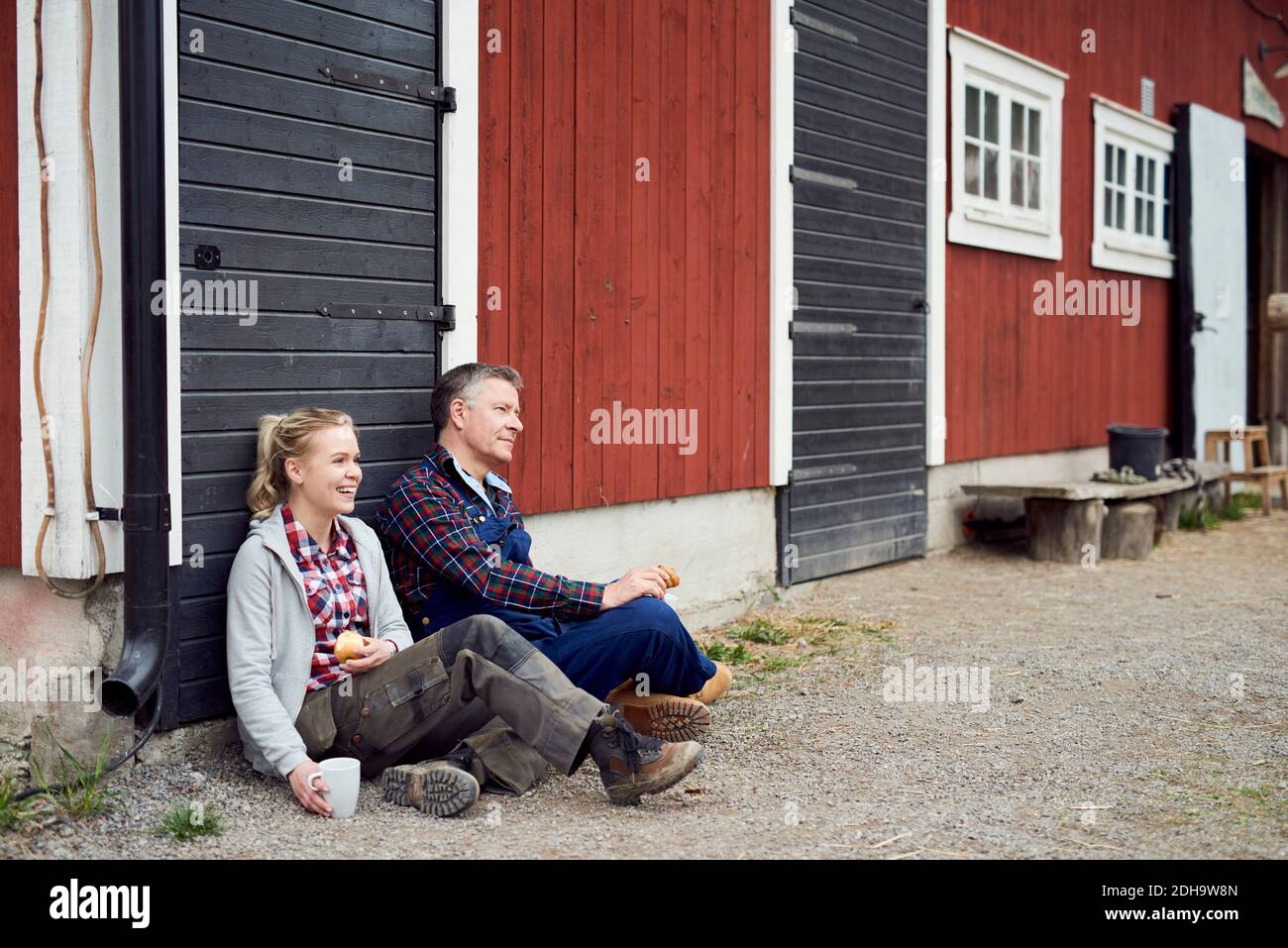 Tutta la lunghezza della figlia e del padre che siedono contro il fienile Foto Stock