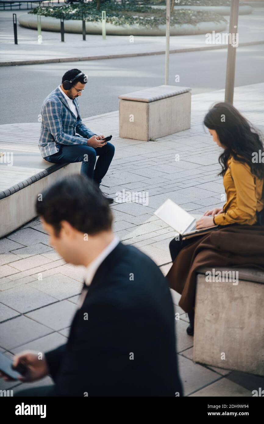 Tre persone che lavorano alla piazza seduti a parte Foto Stock