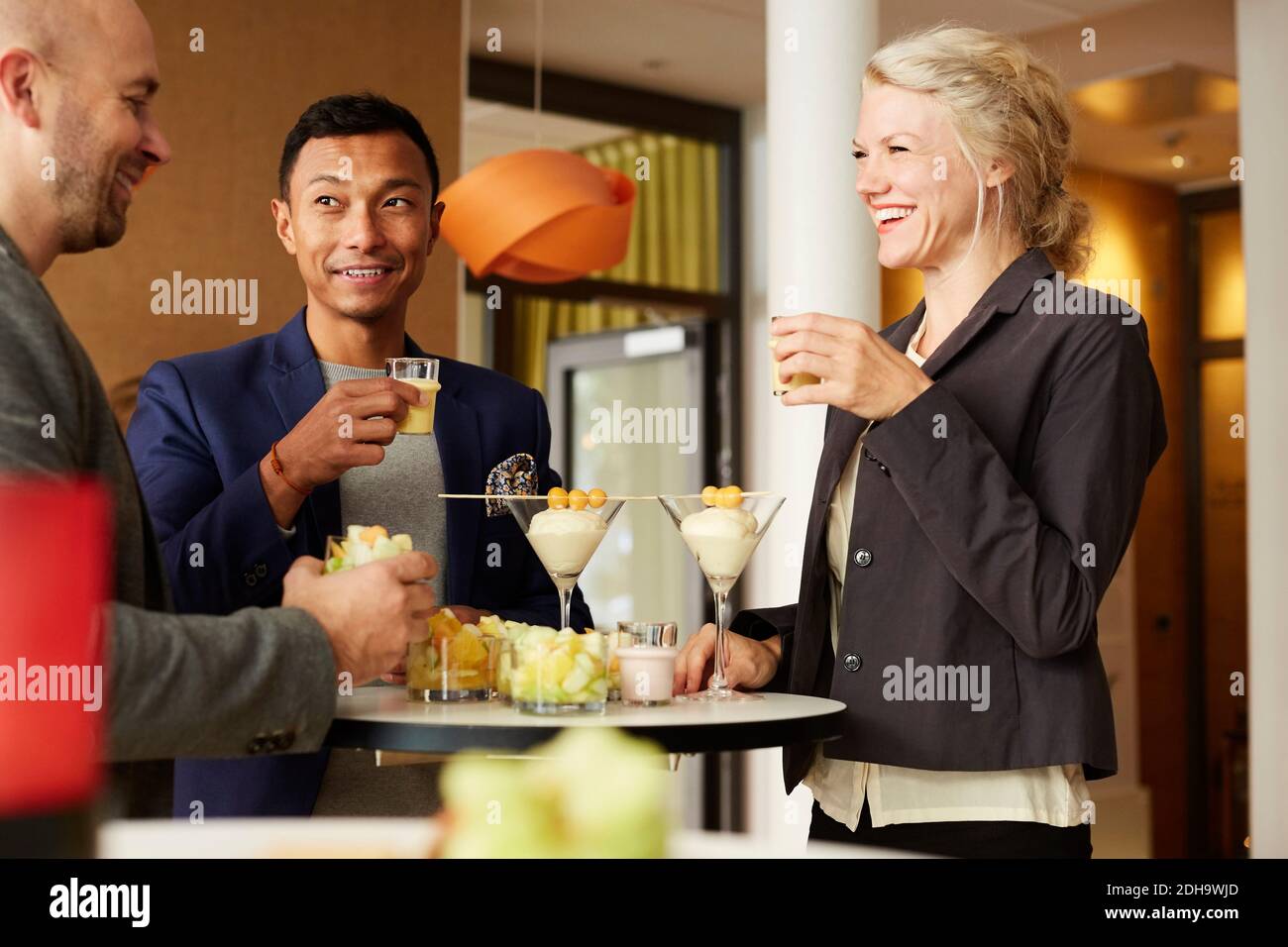 Sorridente gente di affari che parla mentre beve all'officina dell'ufficio Foto Stock