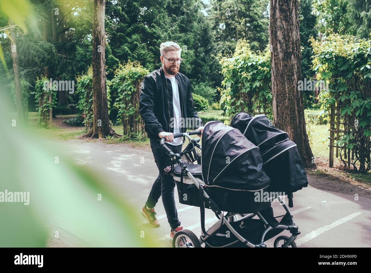 Tutta la lunghezza dell'uomo che spinge il carrello del bambino sul sentiero Foto Stock