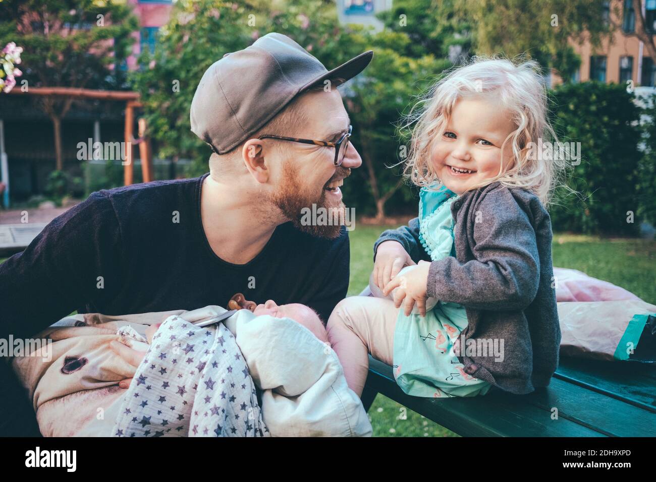 Felice padre che guarda la figlia mentre tiene il figlio nel parco Foto Stock