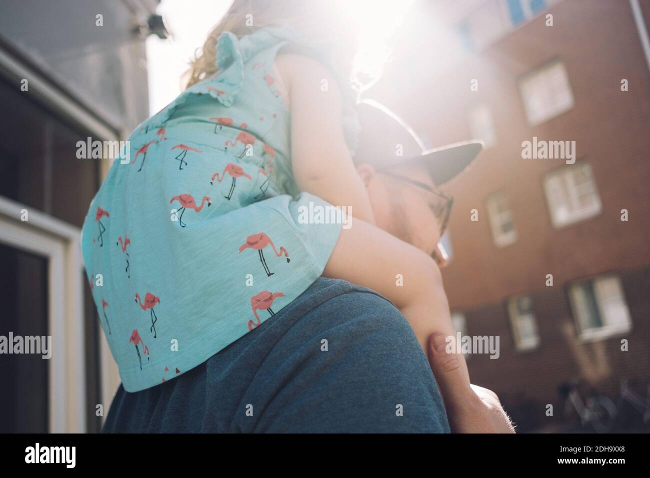 Vista ad angolo basso del padre che porta la figlia sulle spalle città durante il giorno di sole Foto Stock